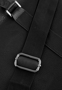 Black textured leather strap with a black webbing section, featuring a silver metal buckle for adjustment.