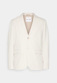 Lysebeige linblazer med enkel knaplukning, reverskrave, to frontlommer og tætsiddende pasform. Blød tekstur med minimalistisk design.