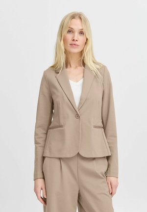 Beige Stoffblazer mit tailliertem Design, einreihiger Knopfverschluss und zwei seitlichen Taschen. Über einem weißen Oberteil getragen, verfügt er über einen klassischen Revers.