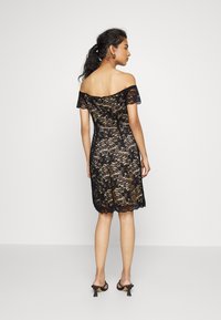 Vestido de renda preta com design à laçadeira, corpete ajustado e corte até ao joelho. Padrão floral notável e detalhe com bainha recortada.