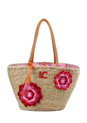 Bolso tote de paja tejido con asas de cuero marrón claro, forro de tela con flores rosas, flores de crochet en rojo y rosa, y detalle de flecos naranjas.