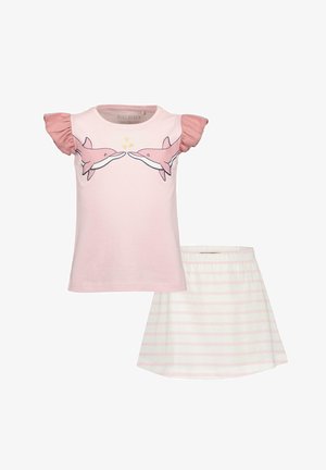 T-shirt in cotone rosa con maniche corte a volant e stampa di delfini, abbinato a una gonna bianca con strisce rosa chiaro.
