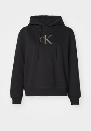 Black hoodie made of cotton blend, featuring a front kangaroo pocket, drawstring hood, and a gold "CK" logo on the chest.