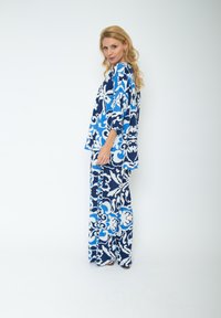 Niebieski i biały zestaw składający się z luźnej bluzki i spodni, z motywem kwiatowym, szerokimi rękawami i swobodnym krojem. Gładka faktura materiału.