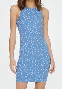 Femme portant une robe sans manches, ajustée, de couleur bleu clair avec un petit motif floral blanc sur fond uni.