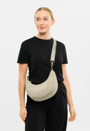 Svetlo šedá semišová kabelka v tvare polmesiaca s širokým popruhom, so striebornými kovovými detailami a hladkým povrchom.