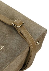 Hnědá semišová taška s texturovaným povrchem, koženým popruhem se zlatou přezkou a hladkým koženým detailem na boku.