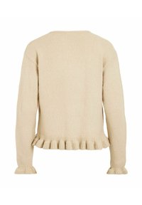 Kremfarget, strikket genser med lange ermer, ribbestrikkede mansjetter og en volangkant nederst. Har rund halslinning og en avslappet passform.