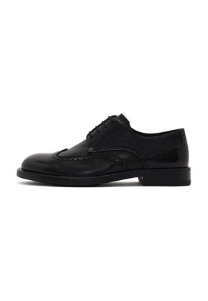 Zapato brogue de cuero negro para hombre con diseño de ala, detalles perforados y cierre de cordones, mostrado de lado sobre fondo blanco.