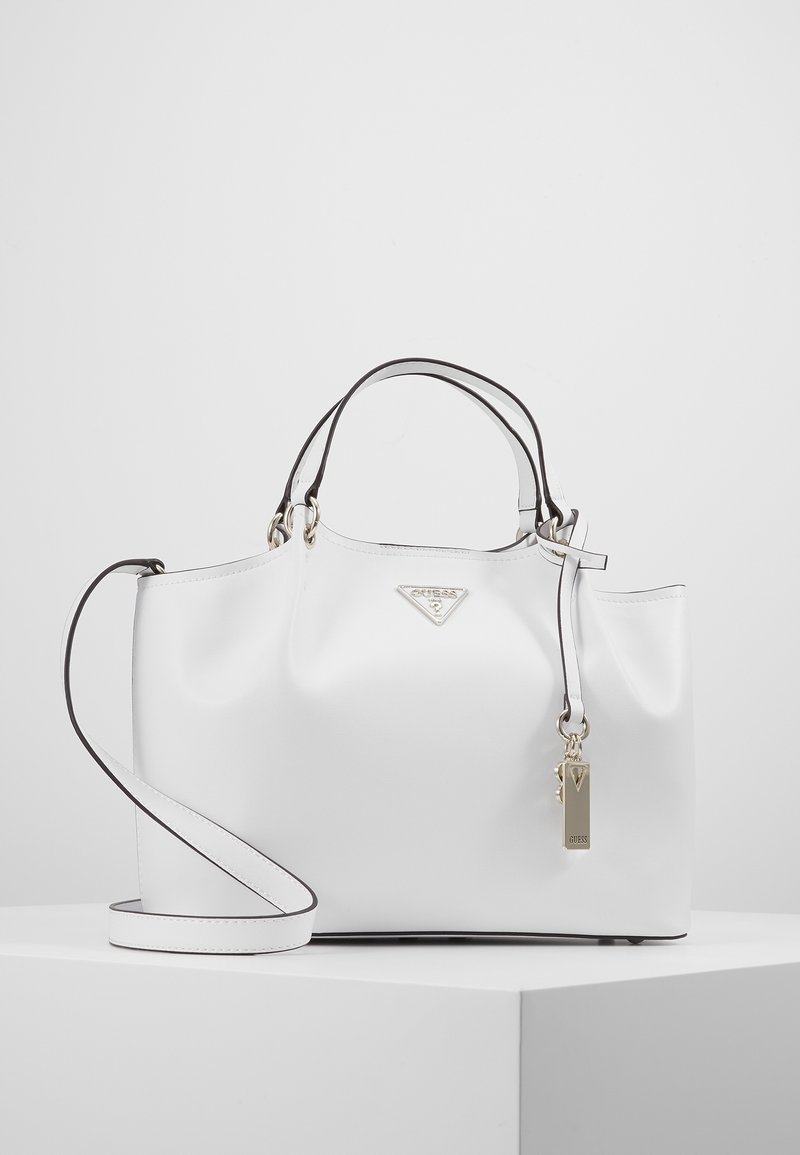 Sac à main synthétique blanc avec quincaillerie argentée, accents noirs et une bandoulière amovible. Présente un logo de marque et une texture lisse.