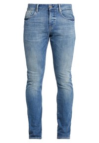 Jeans ajustados de color azul claro, fabricados en denim, con un diseño de cinco bolsillos, textura desgastada y costuras en contraste a lo largo de las costuras.