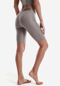 Shorts da ciclismo grigi chiari a vita alta realizzati in tessuto elasticizzato, con una texture liscia e una vita con logo, che raggiungono la metà della coscia.