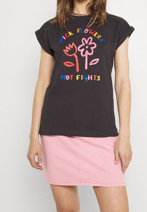 Zwart t-shirt met kleurrijke tekst "Pick flowers not fights" en twee eenvoudige bloem tekeningen, gecombineerd met een lichtroze rok.