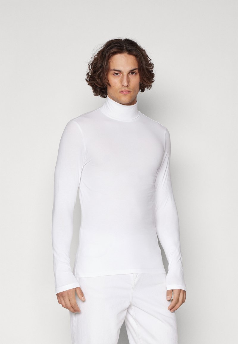 Camisa de cuello alto de manga larga blanca, hecha de un tejido suave y elástico. Diseño ajustado con un cuello alto y agujeros para los pulgares en las mangas.