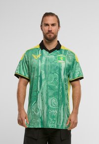 Zöld, rövid ujjú póló absztrakt mintákkal, sárga részletekkel és fekete gallérral. A mellkasán logó található, és textúrált anyagból készült.
