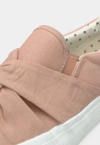 Ingrandimento di una scarpa slip-on rosa con suola bianca e interno a pois.