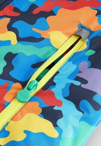 Bunt gemustertes Tarngewebe mit Blau-, Grün-, Orange- und Gelbtönen; ausgestattet mit einem hellgelben Reißverschluss und einem grünen Ziehband, das mit "Little Bird" beschriftet ist.