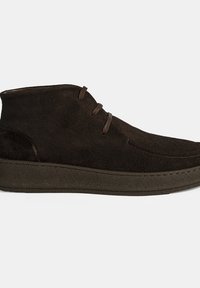 Bruine suède enkellaarsjes met een zachte afwerking, ronde neus, twee oogjes voor veters en een dikke, gestructureerde zool.