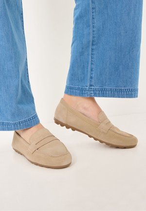 Mocassins en daim beige à profil bas, dotés d'une bande décorative sur le dessus et d'une semelle en caoutchouc texturée pour une meilleure adhérence.