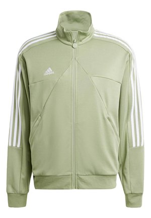 Veste zippée vert clair en tissu doux, dotée d'un col haut, de poches latérales et de trois bandes blanches le long des épaules.