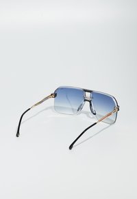 Ochelari de soare cu lentile cu gradient albastru, rame supradimensionate clare, podul accentuat cu aur și brațe negre, având un design elegant și modern.