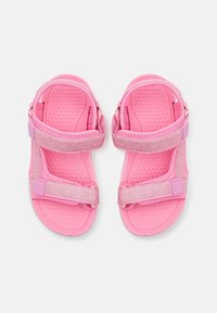 Różowe sandały z teksturowanymi gumowymi podeszwami; regulowane, błyszczące paski; lekka konstrukcja; otwarty fason z wyścieloną wkładką.