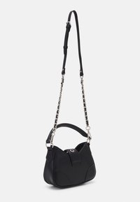 Zwarte leren tas met een gebogen vorm, verstelbare schouderband en zilveren kettingaccenten. Beschikt over een klep sluiting en zijkanten met afgeronde randen.