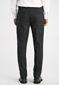 Czarne spodnie służbowe z dopasowanym krojem, z dwiema tylnymi kieszeniami i gładką fakturą, w połączeniu z błyszczącymi czarnymi butami wyjściowymi.