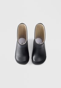 Botas de caucho negras hasta el tobillo con un exterior suave y un interior acolchado. Punta redondeada y suelas texturizadas; diseño minimalista.