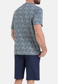 Haut à manches courtes dans un motif de feuilles bleu clair et gris, associé à un short bleu marine foncé, offrant une coupe décontractée et une texture douce.