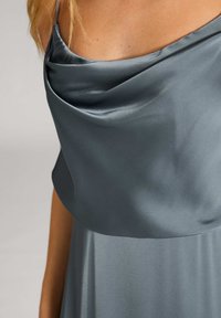Satin-graues Kleid mit drapiertem Ausschnitt und dünnen Trägern, das einen fließenden Rock und eine glatte Textur aufweist.