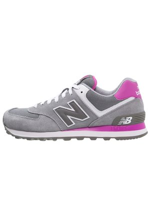Szaro-różowy but do biegania New Balance z białymi sznurowadłami, cholewką z siateczki i zamszu oraz oznaczonymi detalami na podeszwie środkowej i pięcie.