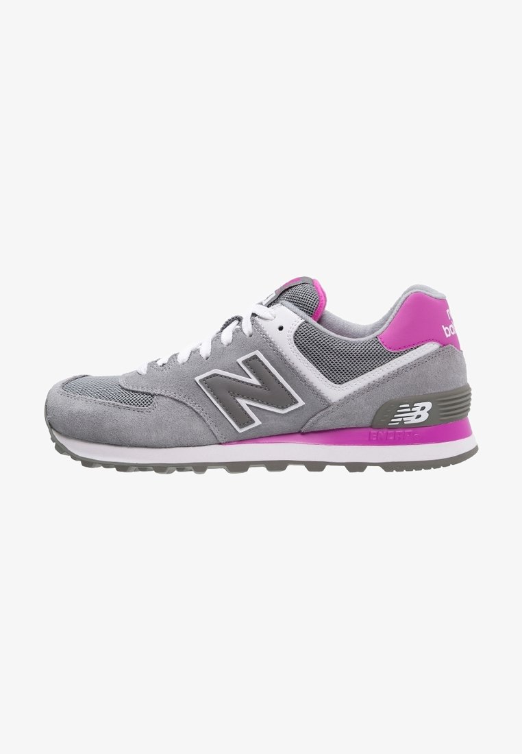 Chaussure de running New Balance grise et rose avec lacets blancs, dessus en mesh et en suède, et détails de semelle intermédiaire et talon brandés.