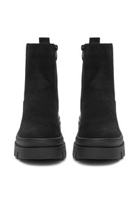 Botas de tobillo de ante negro con una textura suave, que cuentan con cremalleras laterales y suelas de goma gruesa para mayor durabilidad y tracción.