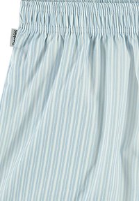 Tissu rayé bleu clair avec une taille élastique froncée. La texture semble lisse avec des rayures blanches verticales. Étiquette visible.