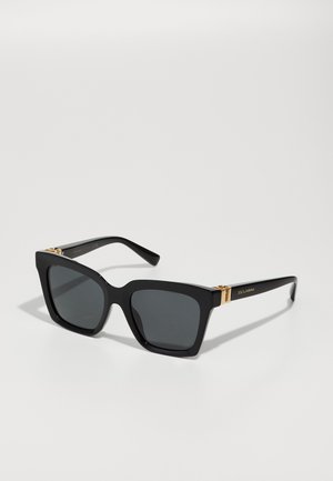 Schwarze übergroße Sonnenbrille mit quadratischer Form, dunklen Gläsern, glänzendem Kunststoffrahmen und goldenen Akzenten an den Schläfen.