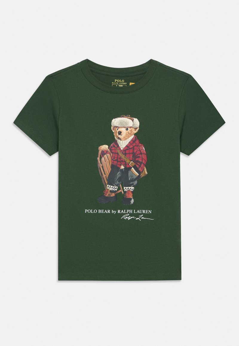 Tricou verde din bumbac, cu un grafic care prezintă un urs îmbrăcat cu o cămașă în carouri roșii și echipament de iarnă, având text dedesubt într-un font cursiv.
