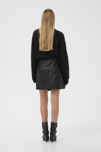 Musthave musta karvane sviiter, kõrge vöökoht must nahkse seeliku, millel on kortsus tekstuur, ja mustad jalatsid kontsadega ankle boots, millel on teravad varbad.