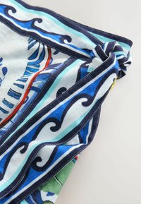 Farebná šatka s potlačou vyrobená z ľahkej látky, s modrými vlnami, zelenými akcentmi a uzlom na jednom konci.