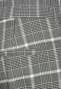 Zwart en witte geruite stof met een mix van houndstooth en ruitpatronen, met een gestructureerd oppervlak en duidelijke contrasterende vierkanten.