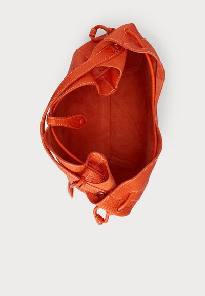 Oranžna usnjena torbica z gladko teksturo, ki ima prostorno notranjost in zatezno vrvico za zapiranje. Natančno šivani detajli po celotni torbici.