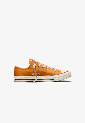 Niedrig geschnittener Sneaker aus orangefarbenem Canvas mit weißer Gummisohle, rosa Streifen, weißen Schnürsenkeln und Metallösen, seitlich auf weißem Hintergrund dargestellt.