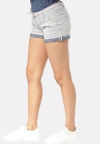 Světle šedé šortky s modrým džínovým manžetou, s elastickým pasem na šňůrku, předními kapsami a strukturovanou tkaninou. Nosené s bílými teniskami.