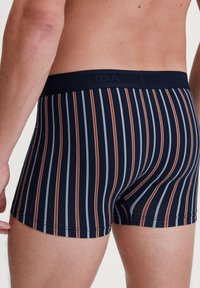 Marineblauwe boxershort met verticale strepen in bruin en lichtblauw. Voorzien van een zachte tailleband met "CALIDA" branding. Gladde katoenblend materiaal.