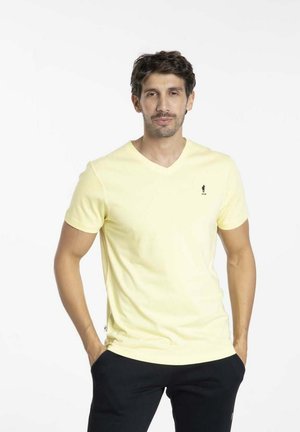 T-shirt jaune clair à col en V fabriqué en coton avec des manches courtes ; présente un petit logo sur la poitrine et une coupe décontractée.