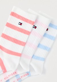 Τρία ζεύγη αστραγάλων κάλτσες με οριζόντιες ρίγες σε κοραλί, ροζ και ανοιχτό γαλάζιο σε λευκό φόντο. Ριμπ υφή; λογότυπο ορατό.