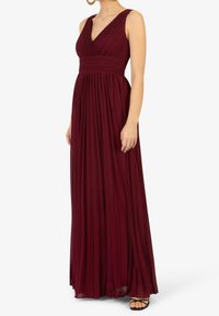 Burgundy maxiklänning med djup V-ringning, plisserad kjol och åtsittande bodice. Tillverkad av lätt tyg, med breda axelband och hel längd.