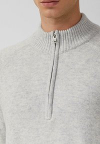 Jasnoszara sweter z zamkiem na szyi, wykonany z dzianiny, z prążkowanym kołnierzem i teksturowanym materiałem, idealny do noszenia na co dzień oraz do warstwowania.
