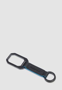 Moschettone nero attaccato a una cinghia in pelle nera con bordi blu e un anello metallico nero su uno sfondo grigio chiaro.