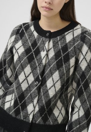 Svart och vit cardigan med argyle-mönster, tillverkad av mjuk ull. Har en rundad halsringning, knapplist och ribbade manschetter och fåll.